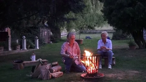 The fire in the fire basket is ignited by the man, the woman watches her husband Video stock 92453698