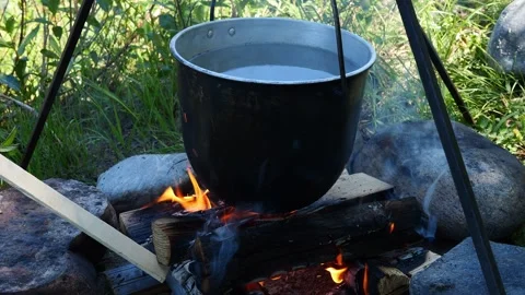 The fire from fire warms water in hanging pot, creating a cozy camping Stock-Footage 279633889