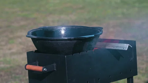 A fire flares up in the brazier and a cauldron lies above it, ready to prepar Stock Footage 185010699