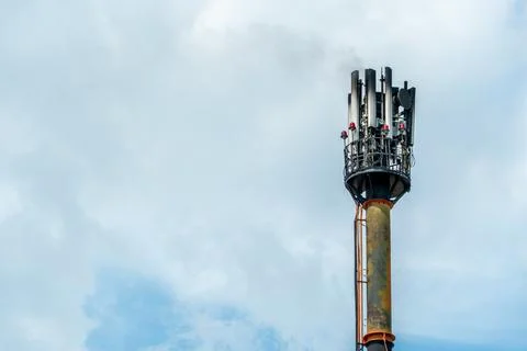 A fire on a GSM antenna on a high tower. On the background of the blue sky, a Stock Photos