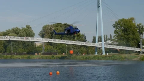Fire helicopter gets ready to drop fire-fighting water bucket on woodland fire Stock Footage 92831460