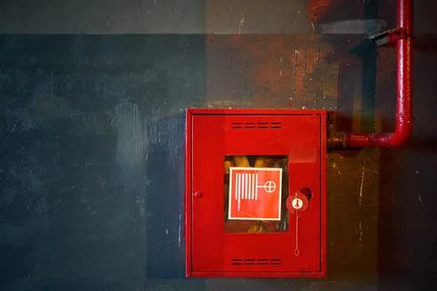 Fire hose in red box. Pipe roll for fire emergency in red metal cabinet on grey Stock Photos