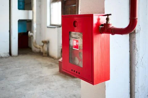 Fire hose in red box. Pipe roll for fire emergency in red metal cabinet on grey Stock Photos