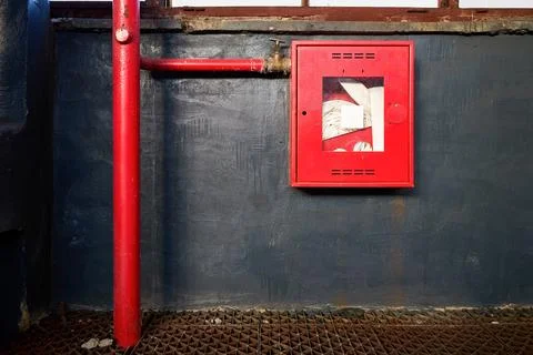 Fire hose in red box. Pipe roll for fire emergency in red metal cabinet on gr Stock Photos
