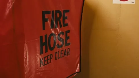 A fire hose stored in a protective case with the text Fire Hose Keep Clear. Video stock 323098066