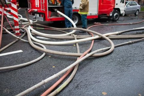 Fire hoses on the background of fire trucks and firefighters at work Stock Photos