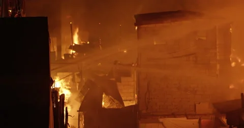 Fire hoses battling Intense fire inferno in poor settlement Stock Footage 65782180