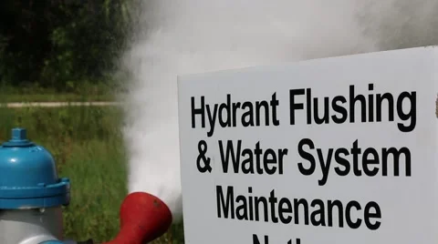 Fire Hydrant Being Flushed in Background of Water System Maintenance Sign Stock Footage 52889328