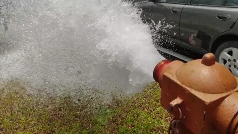 A fire hydrant bursts open, releasing high-speed water in large volumes. Stock Footage 296268002