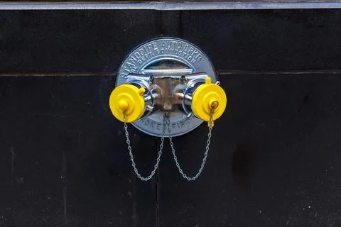 Fire hydrant connection with yellow caps located on city street near building Stockfoto's