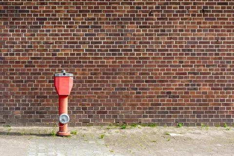 Fire hydrant in front of a brick wall 스톡 사진