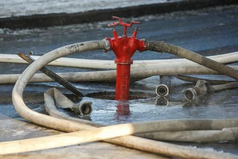 Fire hydrant with hoses floats on the ground during a fire extinguishing 스톡 사진