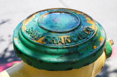 Fire hydrant a little ruined and painted green and yellow with the name of th Stock Photos