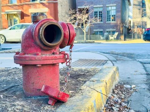 A fire hydrant is located next to the sidewalk in an urban setting. Nearby, t Stock Photos