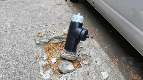 Fire hydrant partially uplifted from the sidewalk alongside a parked car Stock-Fotos