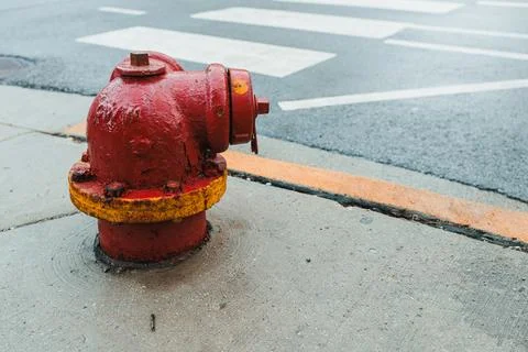 A fire hydrant is placed on the sidewalk near a street crossing. The pavement Stock Photos