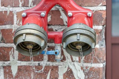 Fire hydrant for a quick set of water on a brick wall. Stock Photos