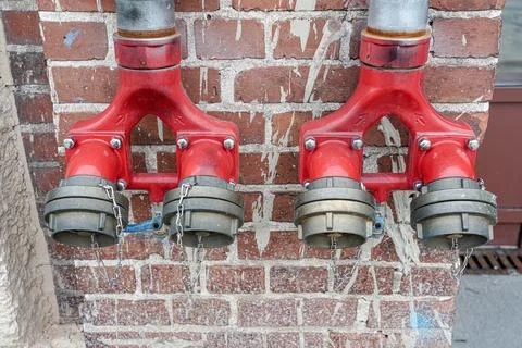 Fire hydrant for a quick set of water on a brick wall. Stock Photos