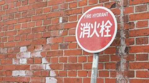 Fire hydrant  sign with red brick wall in japan. Stock Photos
