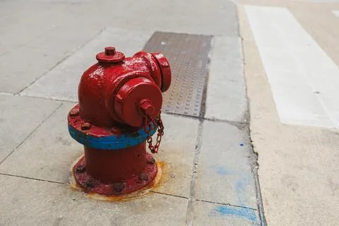 Fire hydrant sits on the sidewalk next to a street. The metal structure has a Stock Photos