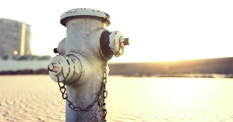 Fire hydrant standing alone at sunset near a cityscape Stock Illustration