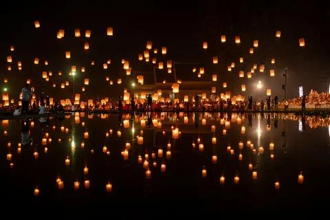 Fire Lanterns Floating up into the sky is reflection in the water at night .. Stock Photos