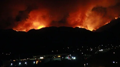 Fire in the mountains, pan down to city below Stock Footage 109203004