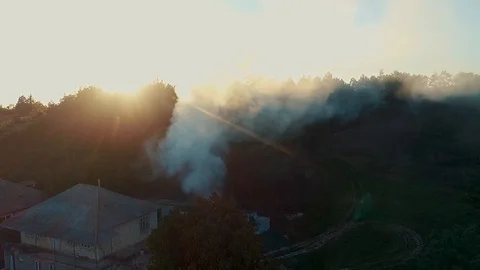 A fire outside a house located in a corner of a village, filmed with a drone  Stock Footage 113315601