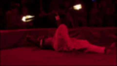 Fire performance of person lying down with audience watching, blur effect, red Stock Footage 340385559