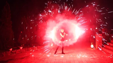 Fire performance show, red sparks at night. Female artist spins sparklers at the Stock Footage 252391439