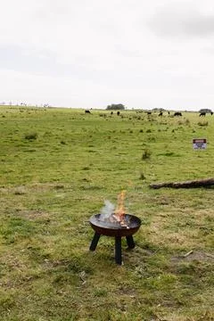 A fire pit on a farm lit with a small fire and eco recycled wood  you can see Stock Photos