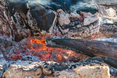 Fire pit with logs burning and charcoal red from heat. Texture, background Stock Photos