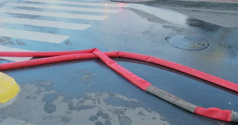 Fire red hose lies on the pavement in the water. Consequences of extinguishing a Stock Footage 221508043