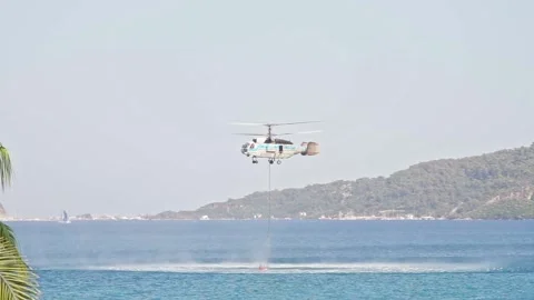 Fire rescue helicopter picks up bambi bucket of water in sea Stock Footage 237007766