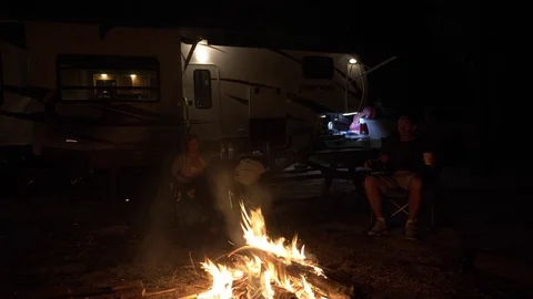Fire Roars with Man and Woman Sit in Front of 5th Wheel RV Stock Footage