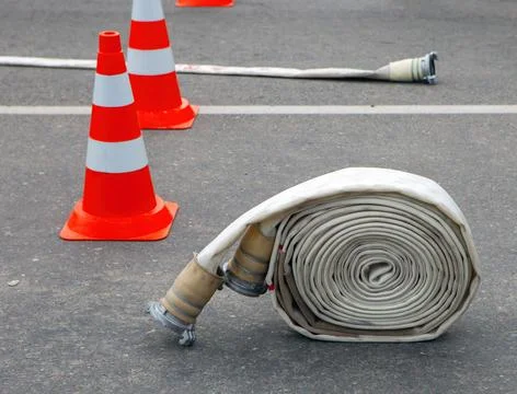 Fire safety training involves a rolled fire hose and traffic cones Stock Photos