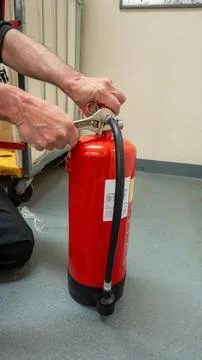 Fire service engineer with a spanner servicing and inspecting an extinguisher Foto stock