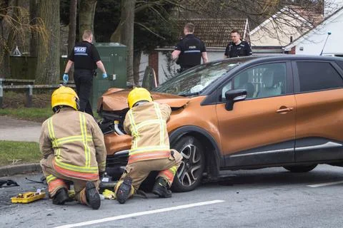Fire service examining a crashed car in the street Stock Photos
