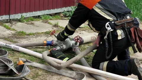 A fire service worker connects fire hoses while extinguishing a fire. Stock Footage 239374648