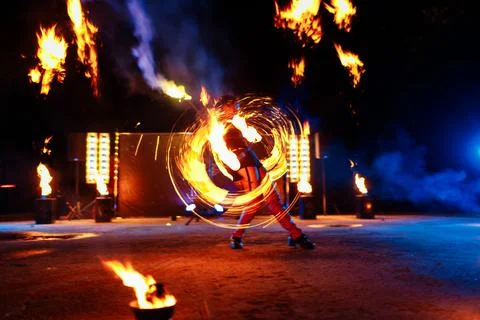 Fire show, dancing with flame, draws a fiery figure in the dark, bright spark Stock Photos