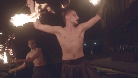 Fire show man twirling ignited poi with group of woman acrobats stilts walking Stock Footage 72915974