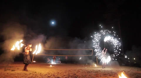 Fire show performance. Male fire performer twirling fire baton and women dance Stock Footage 62193158