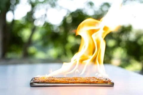 On fire smart phone screen is cracked with blurred background Stock Photos