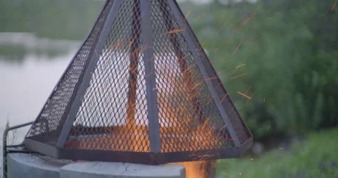 Fire spark at the campfire pit by the lake at evening Stockbeeldmateriaal 130927614