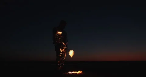 A fire spinner in a silver suit carries torches 動画素材 152328522