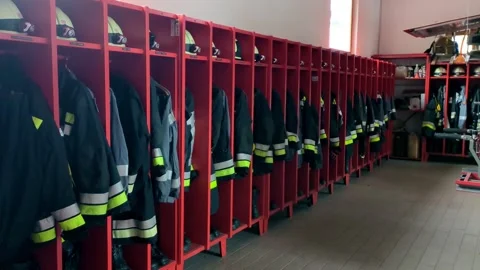 Fire station locker room with red lockers and professional uniforms helmets Stock Footage 331503180