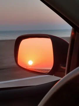 Fire sunset reflected in the rearview mirror of the vehicle Stock Photos