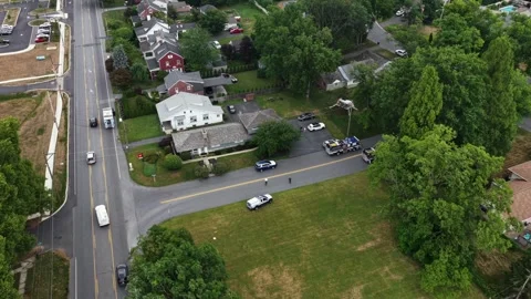 Fire truck and work trucks gather at road intersection near red barn houses in Stock Footage 341842559