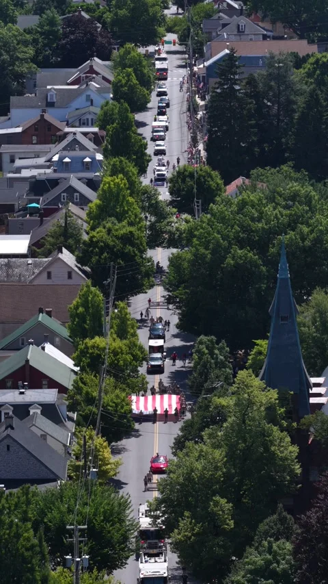 Fire trucks line straight tree-shaded street in slow parade procession Stock Footage 340863768