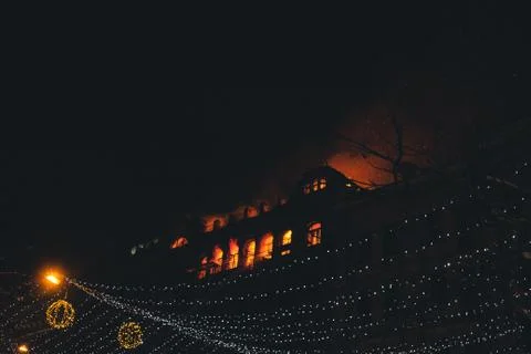 Fire in the windows of the old building at night in winter against the backgr Stock Photos